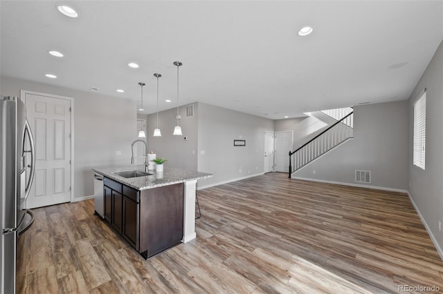 kitchen featuring hanging light fixtures, sink, an island with sink, appliances with stainless steel finishes, and dark brown cabinets