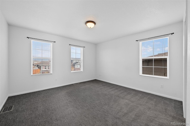 spare room with dark colored carpet