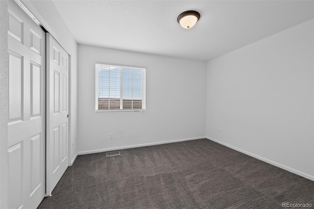 unfurnished bedroom with a closet and dark colored carpet