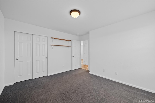 unfurnished bedroom featuring a closet and dark colored carpet