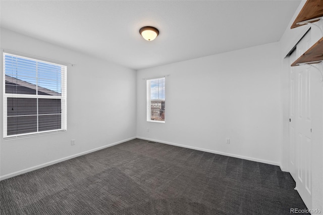 unfurnished room with dark carpet