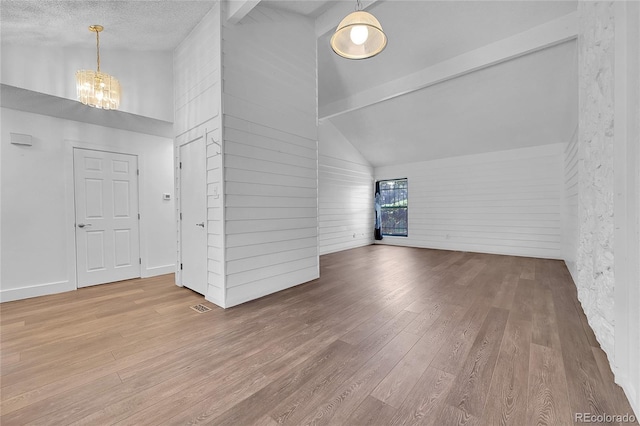 interior space with high vaulted ceiling, a textured ceiling, a notable chandelier, beam ceiling, and hardwood / wood-style floors