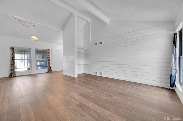 unfurnished living room with hardwood / wood-style flooring, lofted ceiling with beams, and a textured ceiling