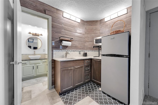 kitchen featuring tasteful backsplash, sink, stainless steel fridge, and a textured ceiling