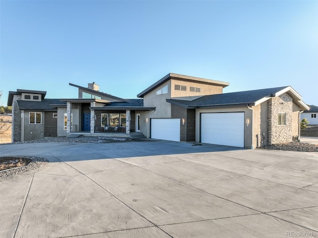 view of front of house with a chimney, stucco siding, an attached garage, and concrete driveway