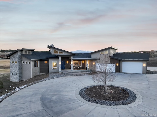 view of front of house with a garage, stucco siding, and curved driveway