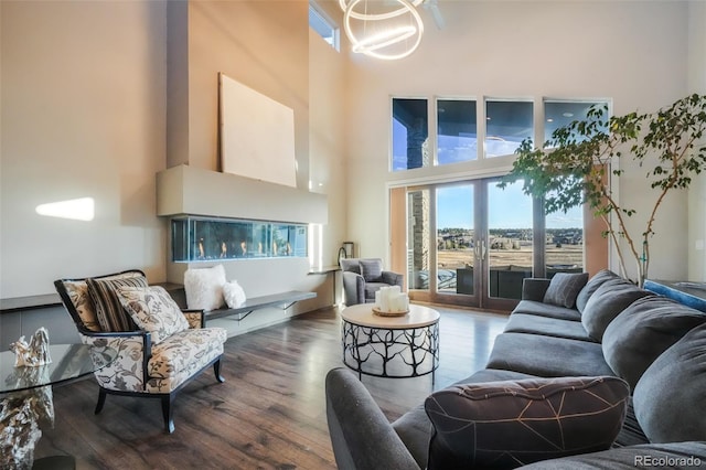 living room with a notable chandelier, a high ceiling, wood finished floors, and french doors