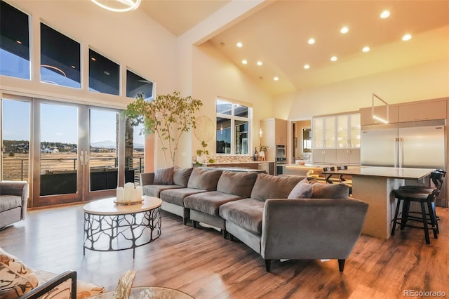 living area featuring recessed lighting, light wood-style floors, and a towering ceiling