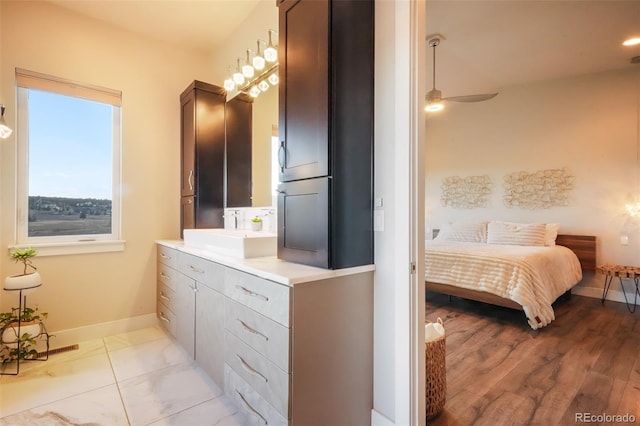 ensuite bathroom featuring baseboards, vanity, ensuite bath, and a ceiling fan