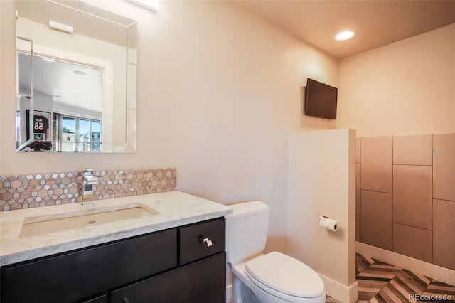 half bathroom featuring vanity, toilet, and recessed lighting