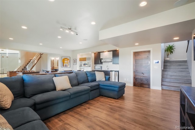 living area with recessed lighting, stairway, baseboards, and wood finished floors