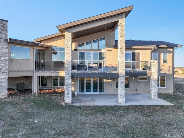 back of property with central AC unit, stucco siding, and a patio