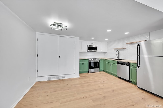kitchen with a sink, visible vents, green cabinetry, and appliances with stainless steel finishes
