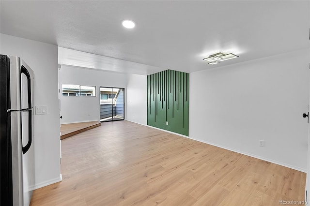 unfurnished room with baseboards and light wood finished floors
