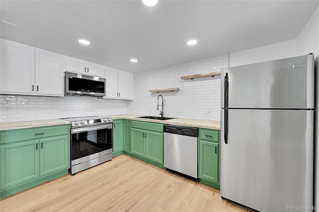 kitchen with green cabinets, a sink, white cabinetry, open shelves, and appliances with stainless steel finishes