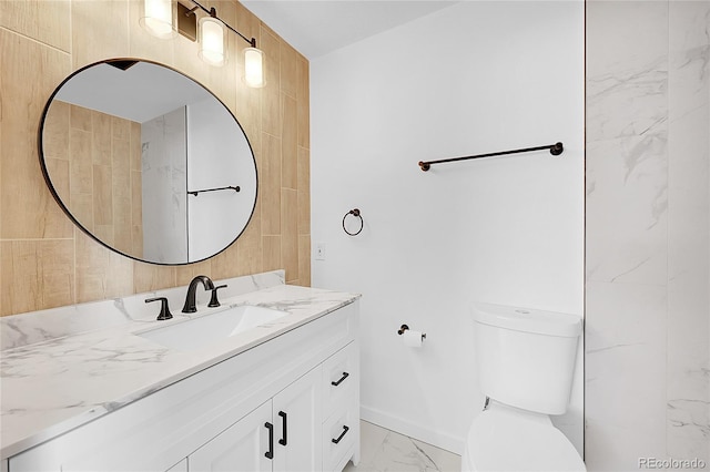 bathroom featuring toilet, baseboards, marble finish floor, and vanity