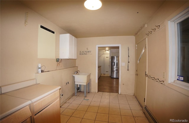 washroom with cabinets, light tile patterned flooring, sink, and a baseboard heating unit