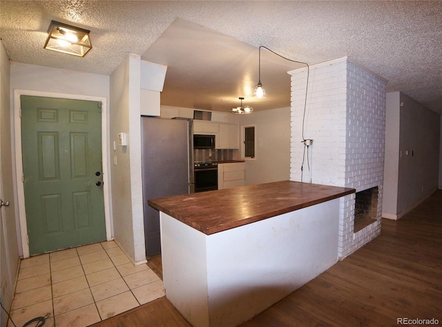 kitchen with butcher block counters, light hardwood / wood-style floors, white cabinetry, appliances with stainless steel finishes, and hanging light fixtures