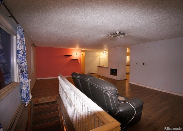 home theater room featuring a fireplace, baseboard heating, a textured ceiling, and dark hardwood / wood-style flooring