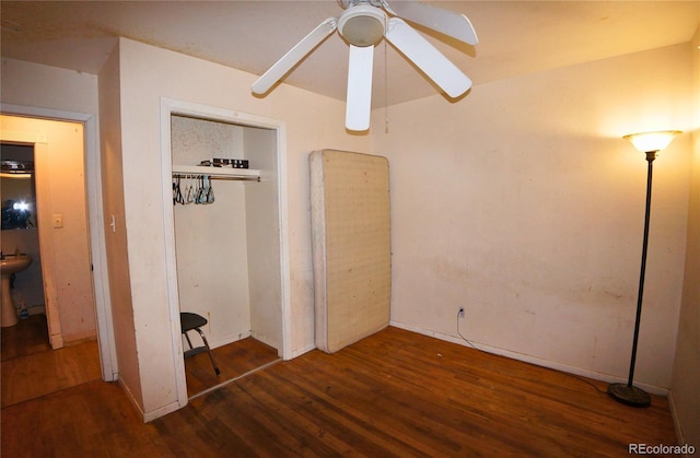 unfurnished bedroom with dark hardwood / wood-style flooring, a closet, and ceiling fan