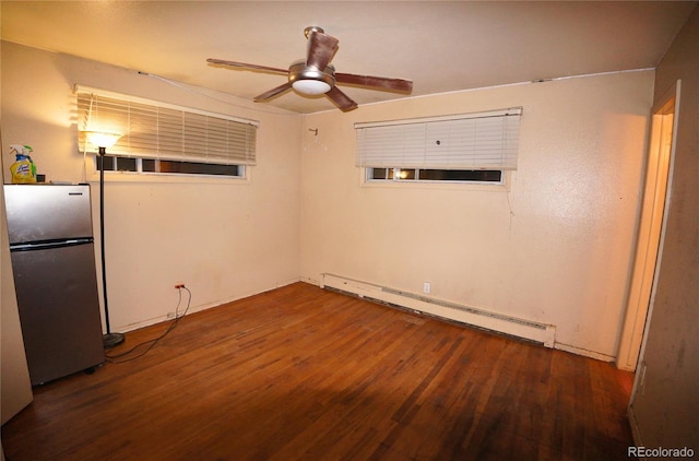 spare room featuring dark wood-type flooring, baseboard heating, and ceiling fan