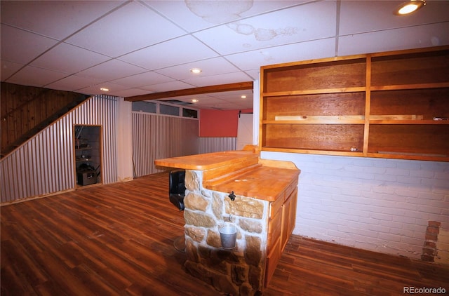 bar featuring dark hardwood / wood-style flooring, wooden walls, a drop ceiling, and butcher block counters