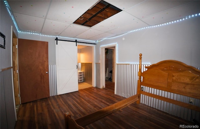 unfurnished bedroom with hardwood / wood-style floors, wooden walls, a barn door, and connected bathroom