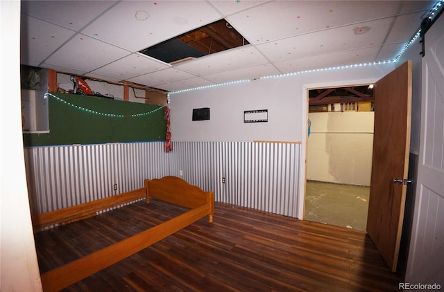 spare room with wood walls, hardwood / wood-style flooring, a barn door, and a drop ceiling