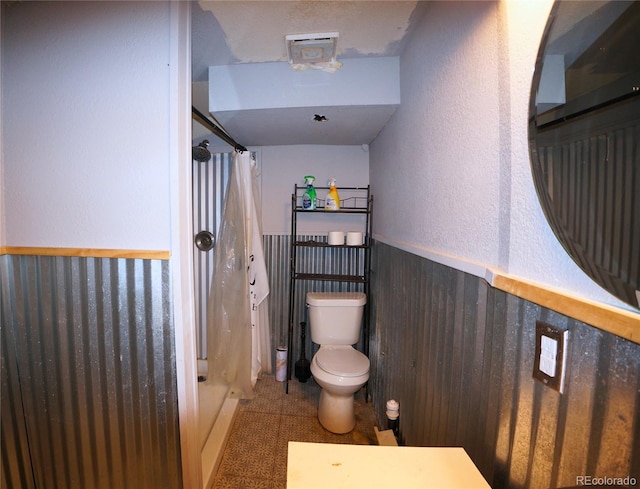 bathroom with walk in shower, wooden walls, and toilet