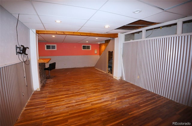 basement featuring a paneled ceiling and hardwood / wood-style flooring