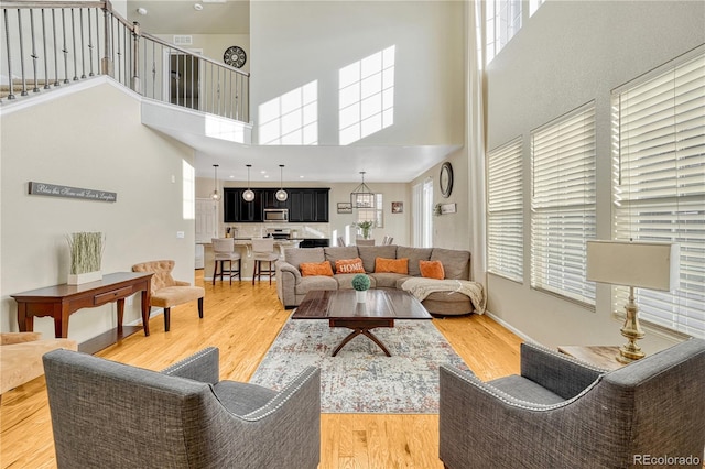 living room with a towering ceiling and light hardwood / wood-style flooring