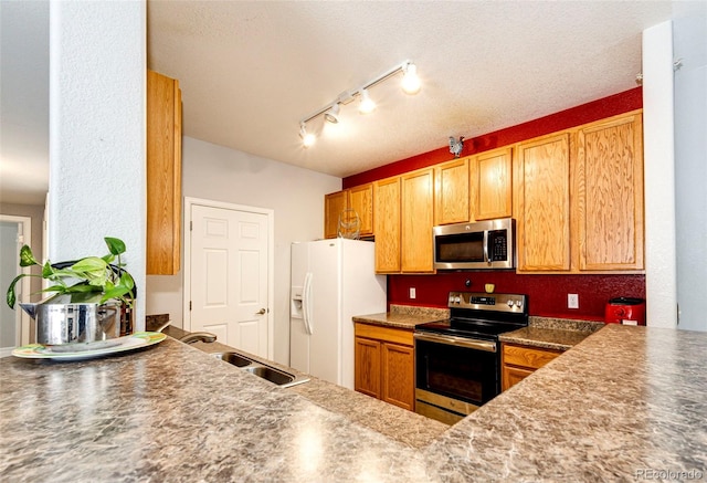 kitchen with stainless steel appliances, a textured ceiling, track lighting, and sink