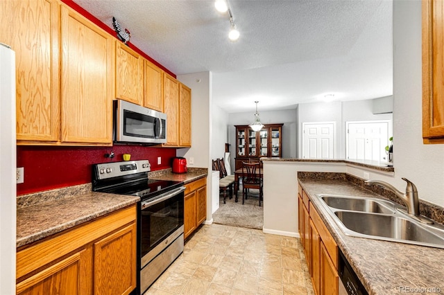 kitchen with appliances with stainless steel finishes, light tile floors, pendant lighting, a textured ceiling, and sink