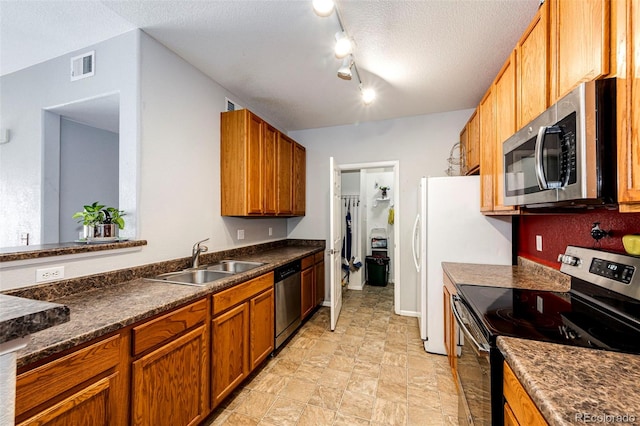 kitchen with appliances with stainless steel finishes, sink, light tile floors, a textured ceiling, and rail lighting