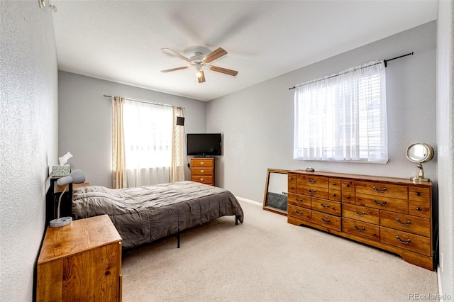 bedroom featuring multiple windows, ceiling fan, and light colored carpet