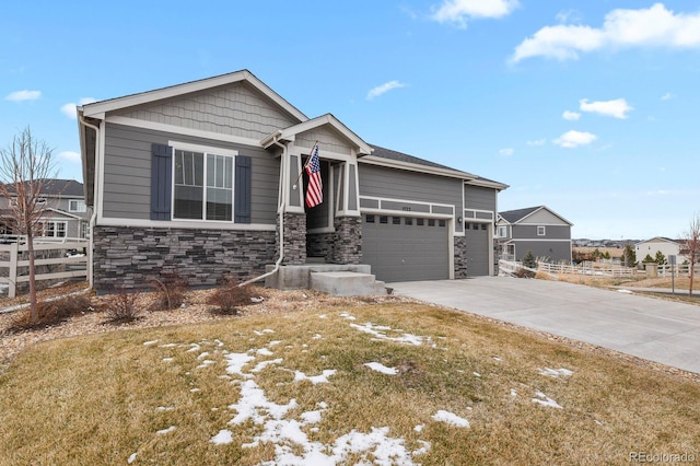 view of front of house featuring an attached garage, stone siding, fence, and concrete driveway