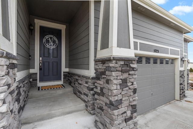 property entrance featuring a garage and stone siding