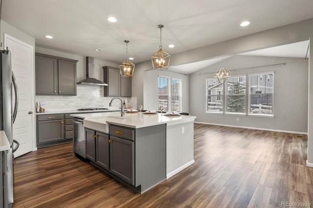 kitchen with decorative backsplash, dark wood finished floors, light countertops, gray cabinetry, and wall chimney range hood