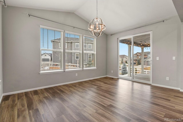 spare room featuring lofted ceiling, a notable chandelier, baseboards, and wood finished floors