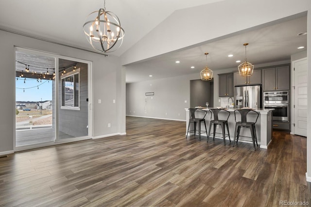 kitchen featuring stainless steel appliances, dark wood-type flooring, a center island with sink, and a kitchen breakfast bar