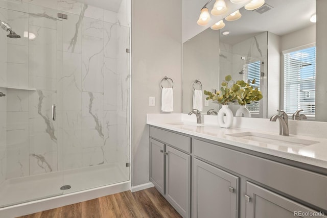 full bath with visible vents, a sink, a marble finish shower, and wood finished floors