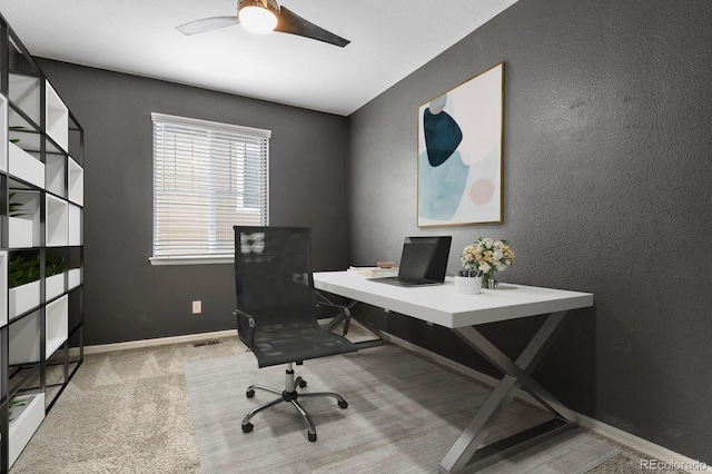 office space featuring a ceiling fan, carpet, a textured wall, and baseboards