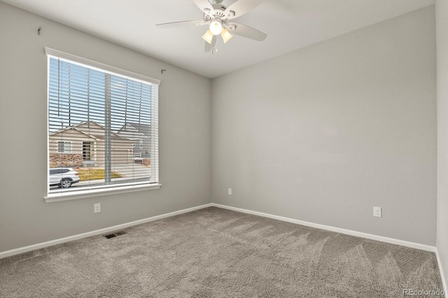 carpeted spare room with ceiling fan, visible vents, and baseboards