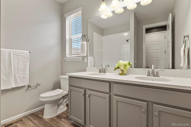 full bathroom featuring visible vents, a sink, a tile shower, and toilet