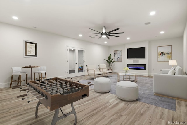 living room featuring wood finished floors, a glass covered fireplace, and recessed lighting