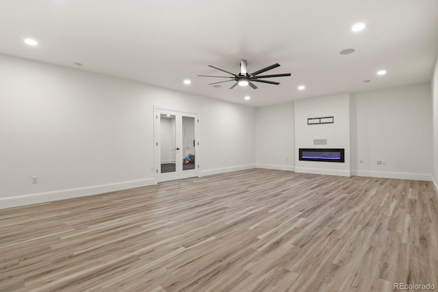 unfurnished living room with ceiling fan, recessed lighting, baseboards, light wood-style floors, and a glass covered fireplace