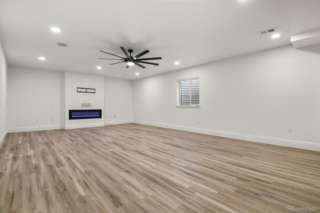 unfurnished living room featuring recessed lighting, visible vents, a ceiling fan, light wood finished floors, and a glass covered fireplace