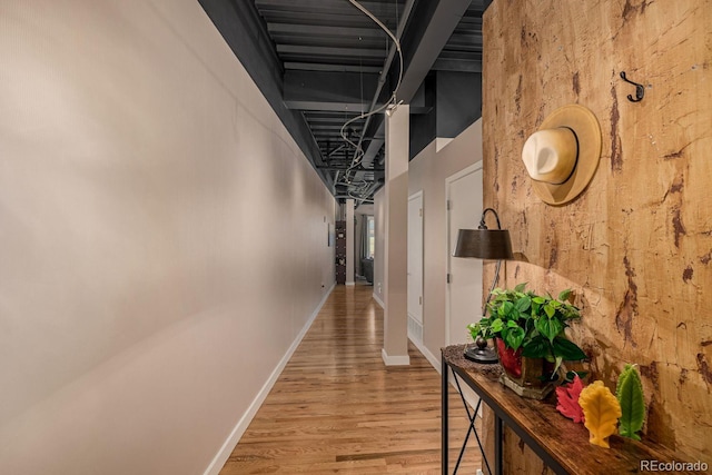 hall with a high ceiling, light wood-style flooring, and baseboards