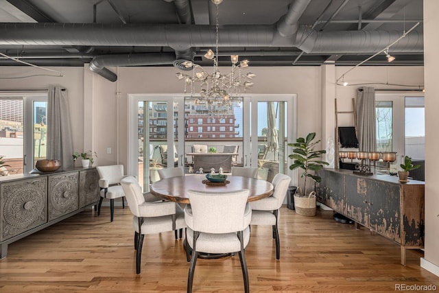 dining space featuring a wealth of natural light, wood finished floors, and an inviting chandelier