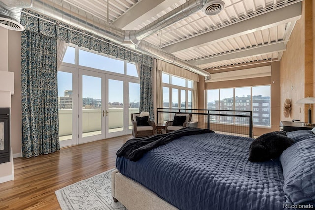 bedroom with visible vents, wood finished floors, access to exterior, a view of city, and french doors